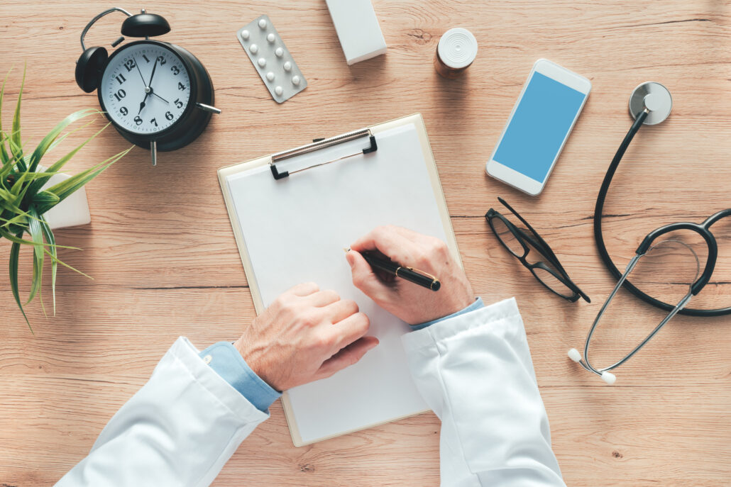 Physician preparing a year-end tax checklist for 2025 surrounded by clock, stethoscope, and paperwork.