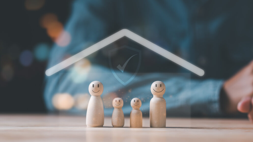 Wooden family figures under a glowing roof symbolizing insurance protection and financial security for doctors.