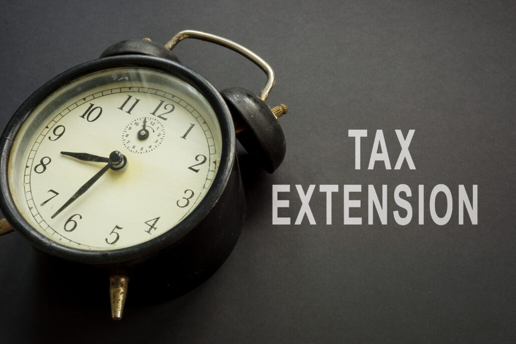 Vintage alarm clock next to the words “Tax Extension” on a dark background.