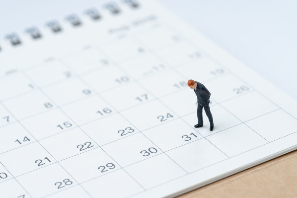 Miniature businessman figure standing on a calendar near December 31, symbolizing year-end tax and giving deadlines for doctors.