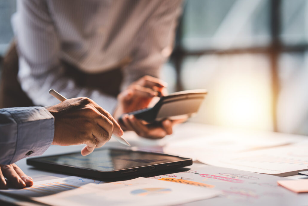 Hands reviewing financial documents with a tablet and calculator during a year-end tax planning session.
