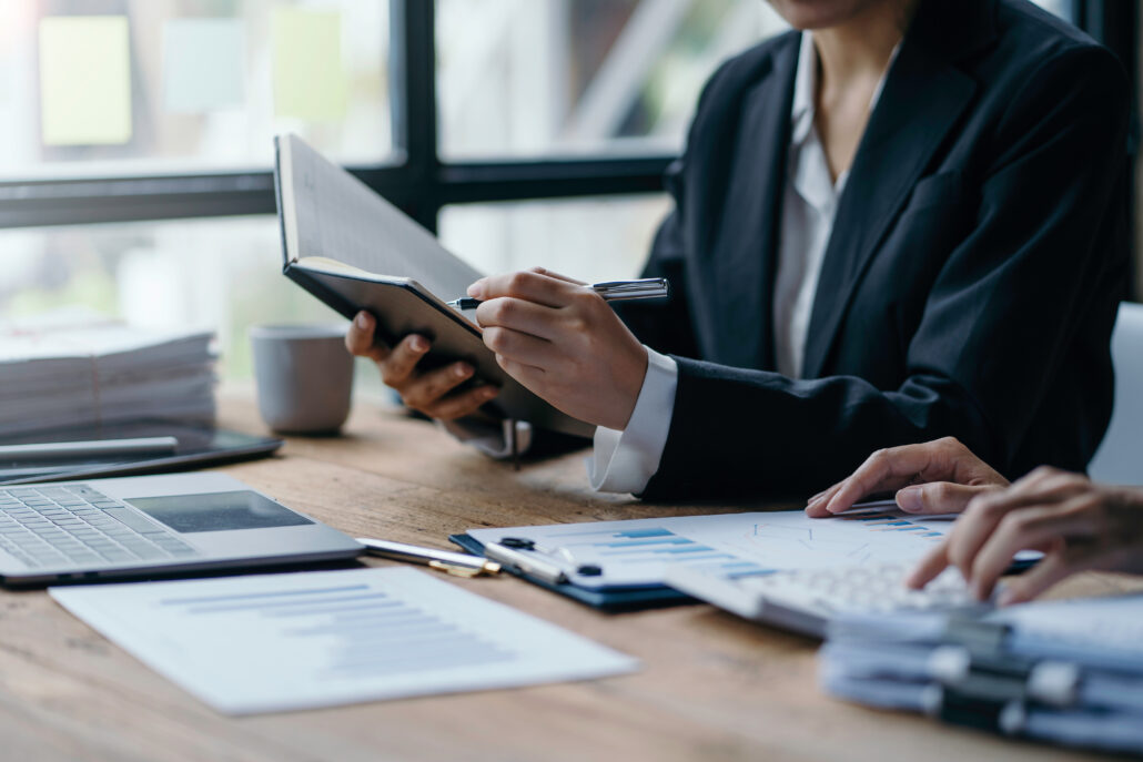 Business owners reviewing quarterly tax estimate documents with charts, a laptop, and a notebook during a planning meeting.