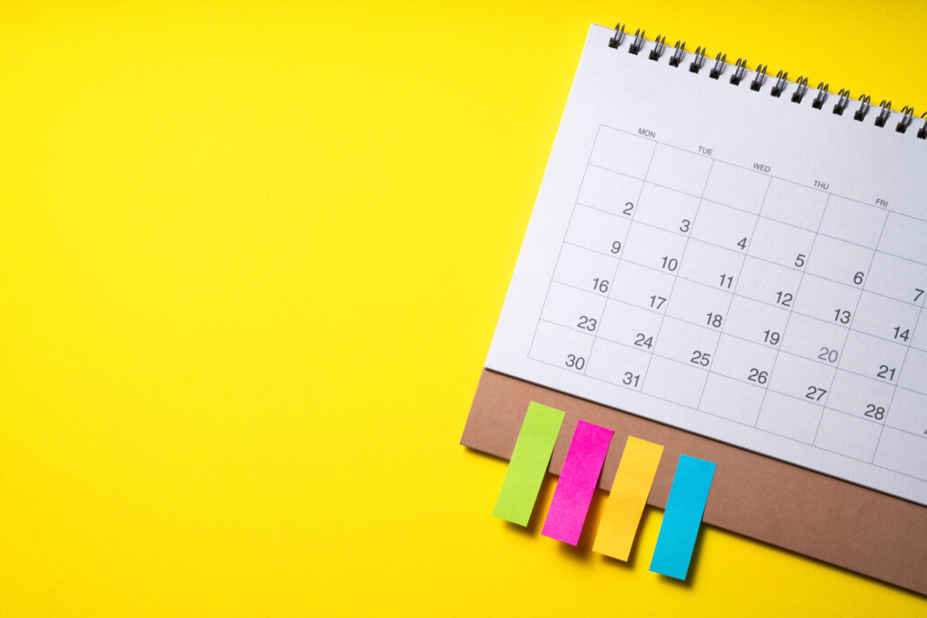 Top-view calendar with colorful sticky tabs on a bright yellow background representing January tax planning deadlines for physicians.